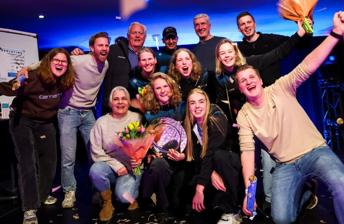 Het marathonschaatsteam viert de winst in het ploegenklassement samen met sponsoren Puur ICT en BTZ. Een feestelijk moment met blije gezichten en trotse teamleden langs de baan.