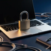 Hangslot op laptoptoetsenbord omringd door ethernetkabels en notitieboekje, symboliseert cybersecurity op kantoor.