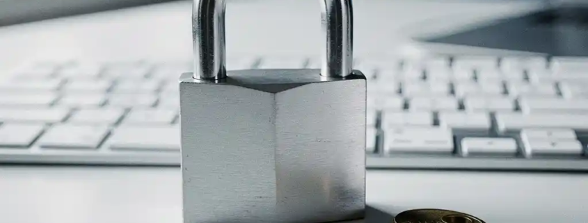 Stalen hangslot met messing sleuteltje op modern toetsenbord, symboliseert digitale beveiliging en cybersecurity.