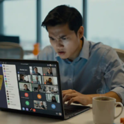 Gefrustreerde medewerker achter laptop met Microsoft Teams-dashboard, afgekoelde koffie en sticky note op bezel, modern kantoor met noordelijk daglicht.