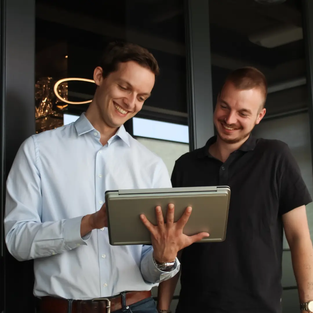 Microsoft 365 Twee medewerkers van Puur ICT kijken samen naar een laptop en bespreken wat er op het scherm staat.