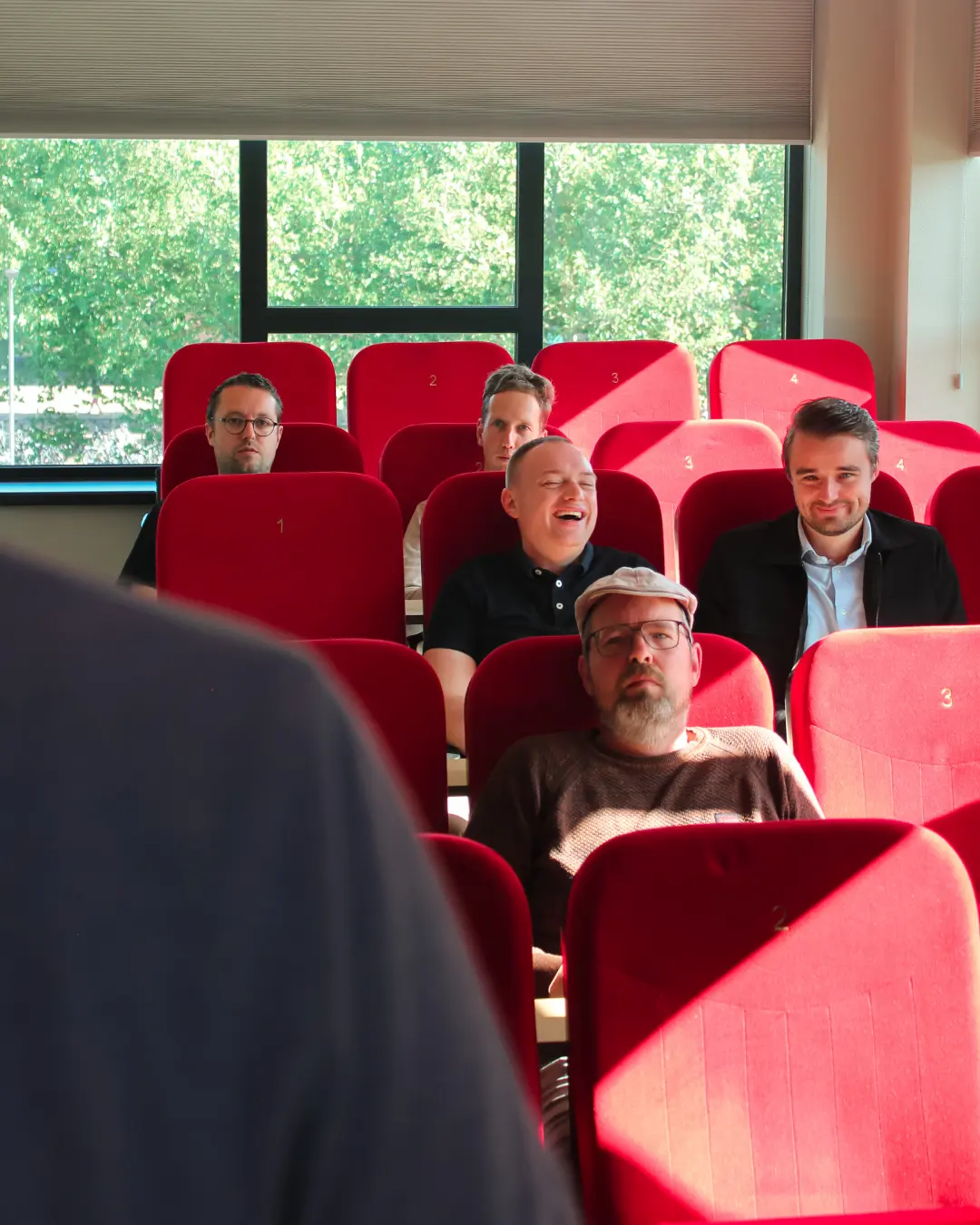 Microsoft 365 trainingen Collega’s van Puur ICT zitten in een vergaderruimte en kijken naar een collega die een presentatie geeft.