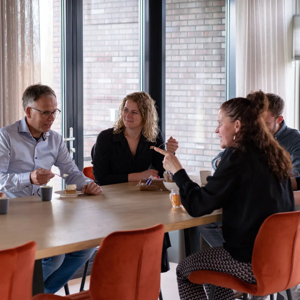 Een groep collega’s van Puur ICT zit samen aan de lunchtafel en is met elkaar in gesprek.