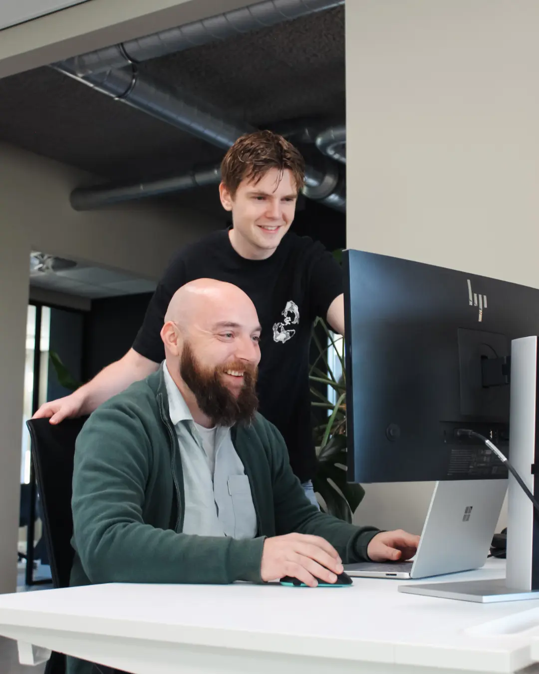 Twee medewerkers van Puur ICT overleggen op de servicedesk en kijken samen naar het computerscherm.