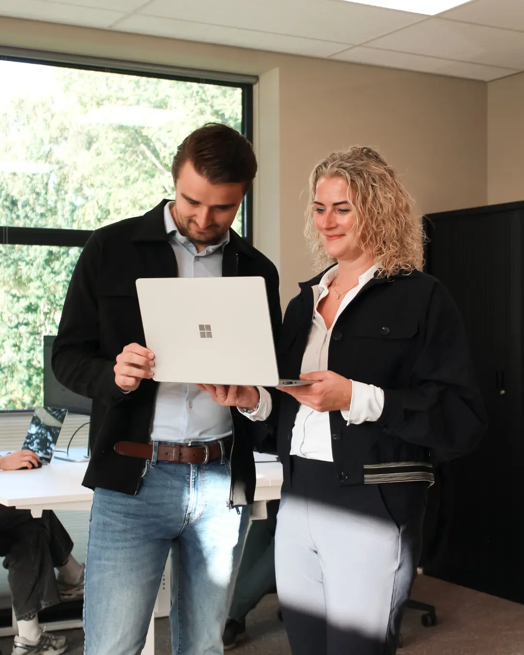 Twee medewerkers van Puur ICT staan samen bij een laptop, terwijl één van hen naar het scherm wijst.